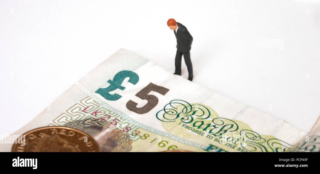 Une figurine miniature homme en costume à la recherche lors d'une note de 5 livres britanniques Banque D'Images