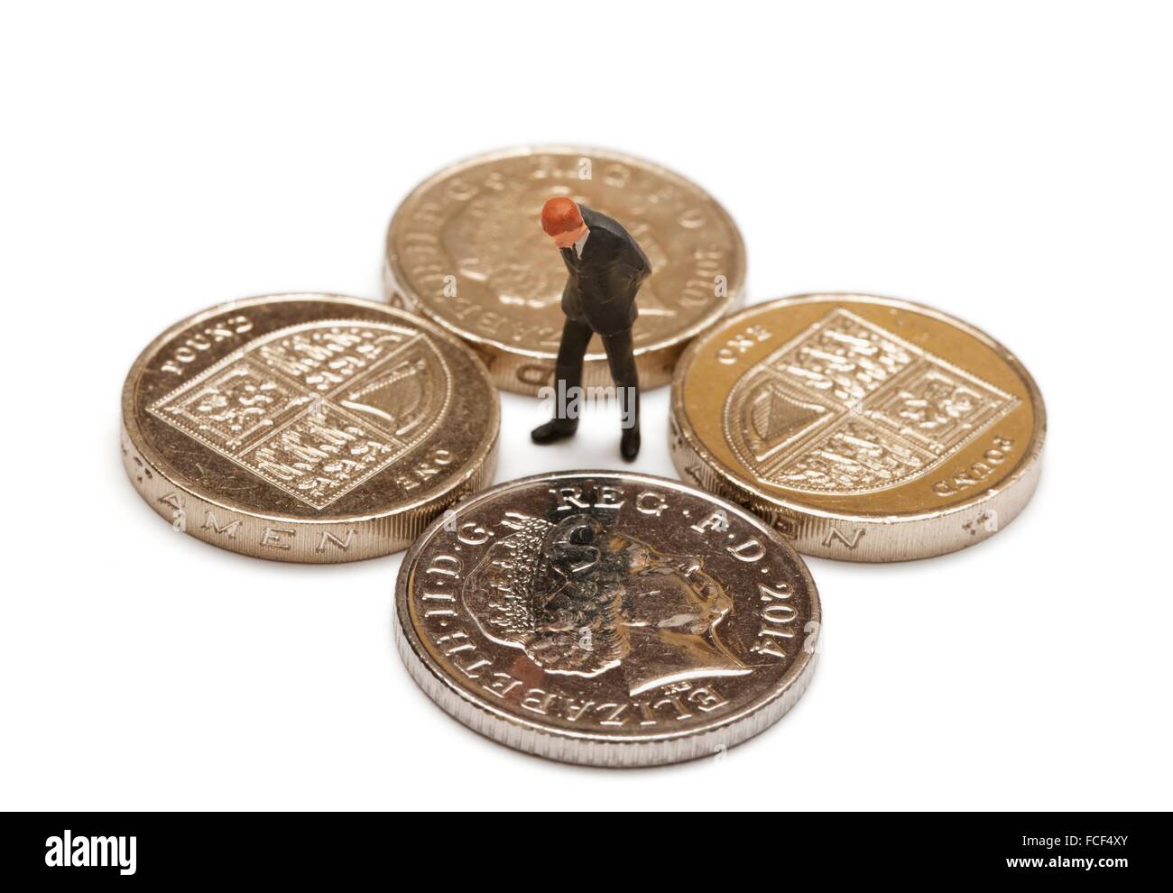 Une figurine miniature homme en costume à la recherche d'une livre des pièces de monnaie et une pièce de 10 pence Banque D'Images