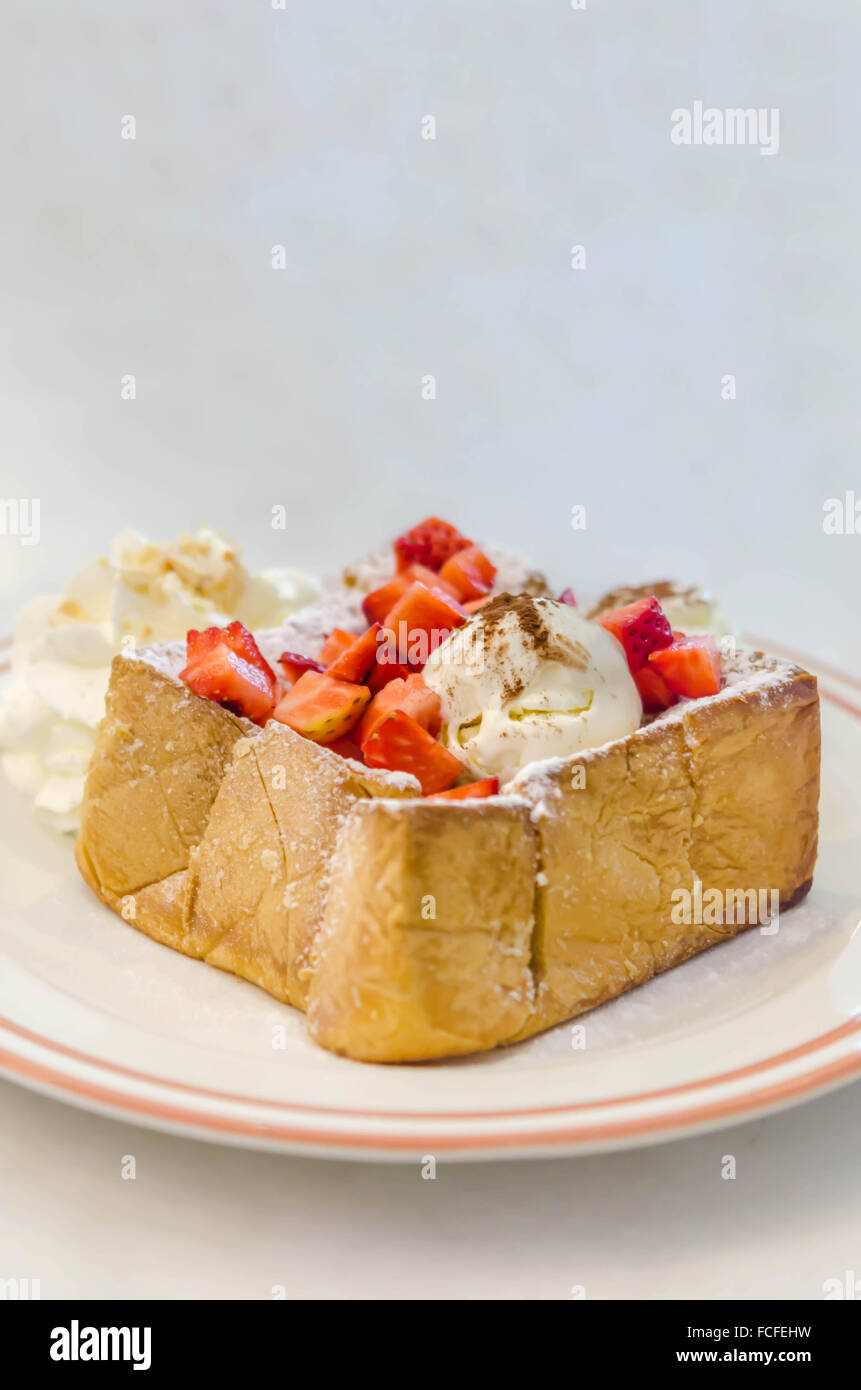 Toast au miel fraises avec de la crème glacée et la crème fouettée Banque D'Images