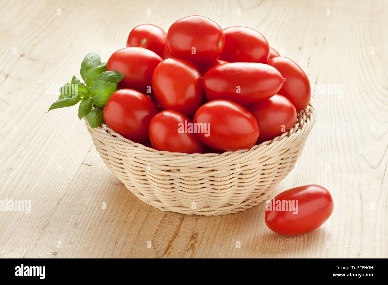 Panier avec des tomates rouges frais et feuilles de basilic vert Banque D'Images