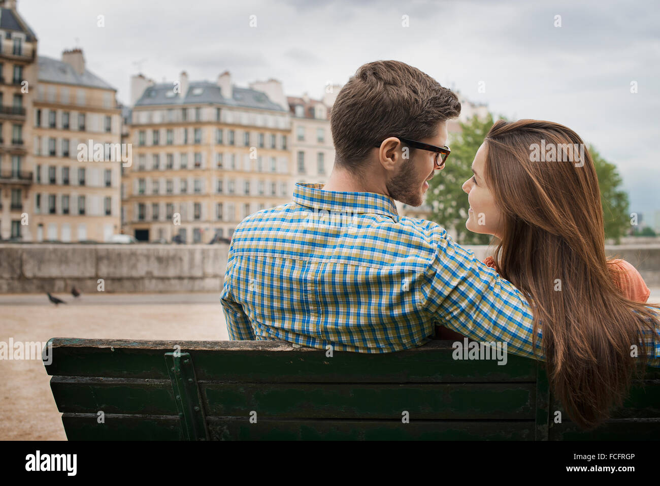 Un couple, homme et femme assis ensemble sur un banc au bord de la Seine. Banque D'Images