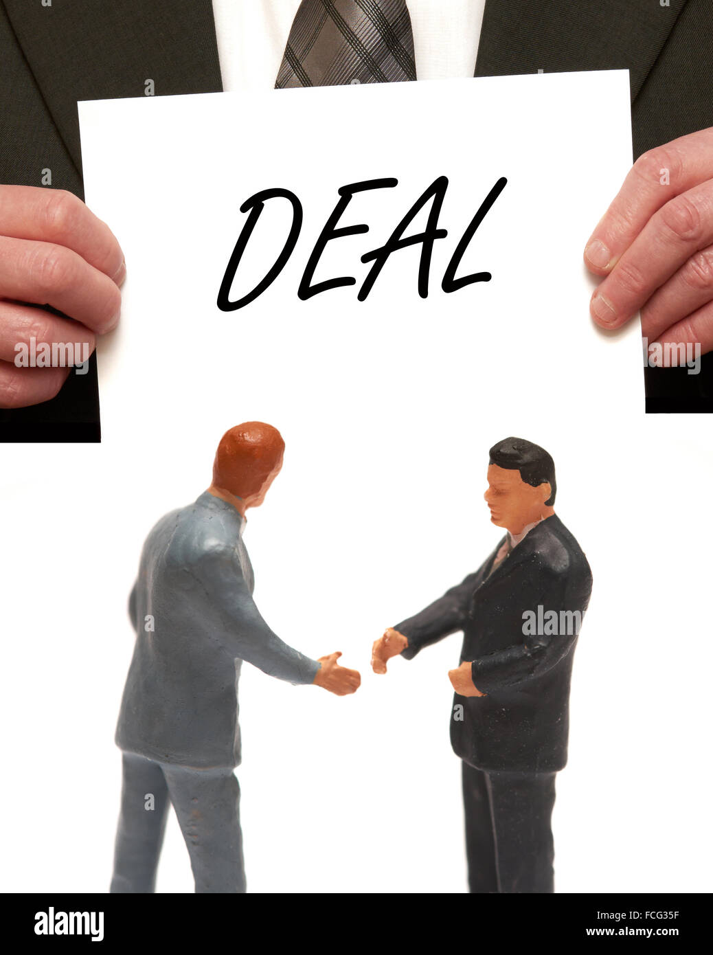 Traiter concept 2 miniatures en costumes shaking hands Banque D'Images