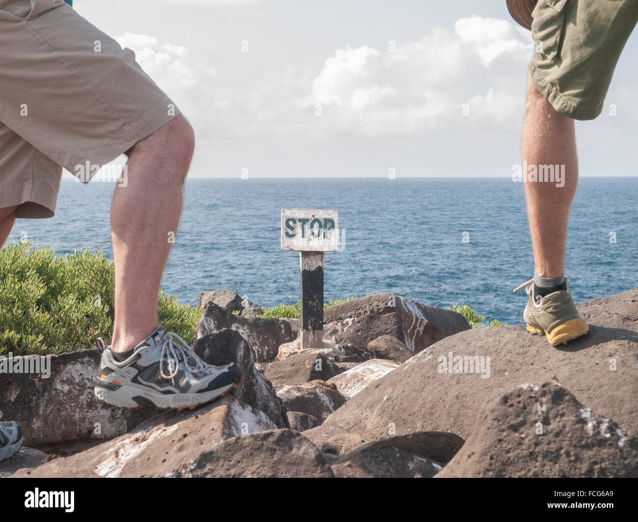 Les jambes de deux mâles dans des chaussures de course à bord d'une falaise  en face d'un panneau d'arrêt par la mer dans des îles Galapagos, en  Équateur Photo Stock - Alamy