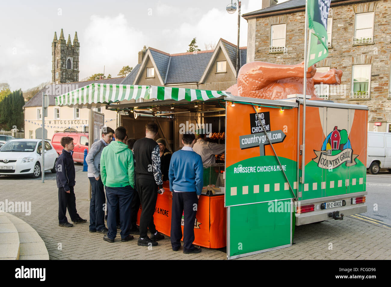 Groupe de garçons font la queue dans un van de restauration mobile, vendant des produits à base de poulet, au marché du vendredi à The Square, Bantry, Irlande. Banque D'Images