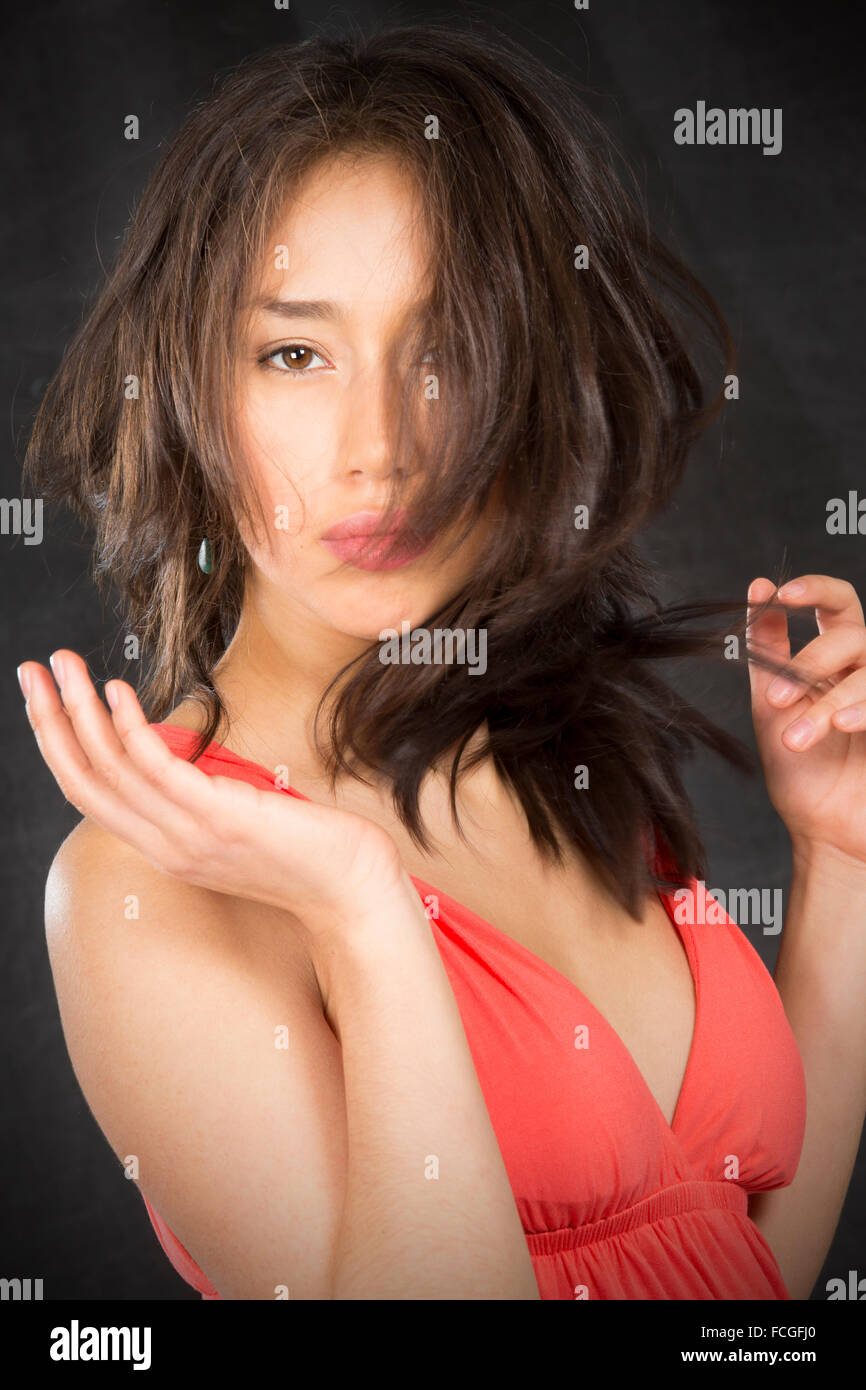 Closeup portrait de belle jeune femme avec des cheveux foiré plus de la moitié de la face, en robe de mandarine sur fond noir.. Banque D'Images