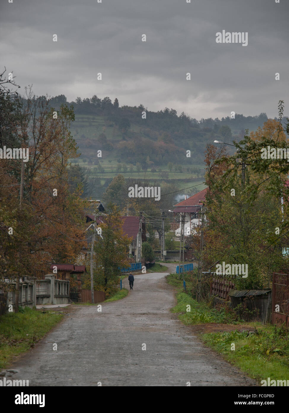 Seul descendant mâle longue route vers village dans la région de Maramures, Roumanie, Europe sur un jour nuageux ciel voilé. Banque D'Images