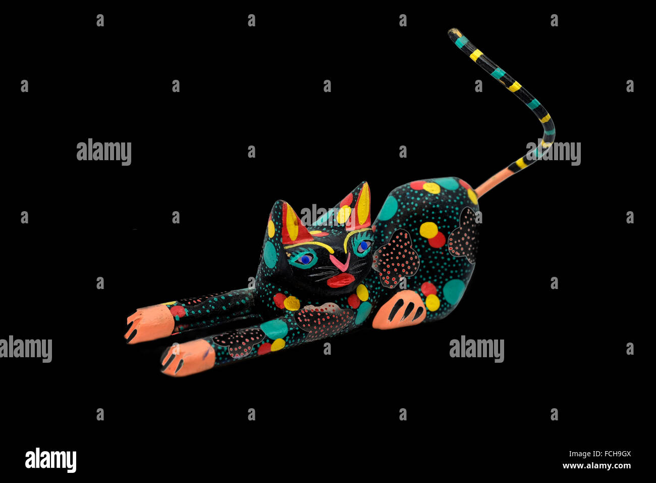 Figurine chat sculpté mexicaine ,très stylisé et coloré, cut-out sur un fond noir Banque D'Images