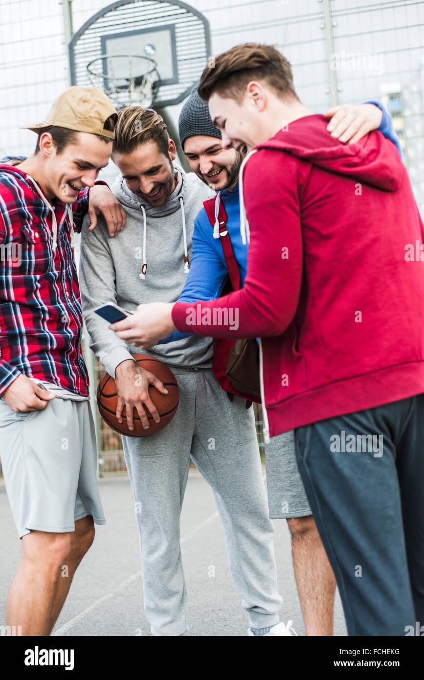 Les jeunes joueurs de basket-ball de rire smartphone Banque D'Images