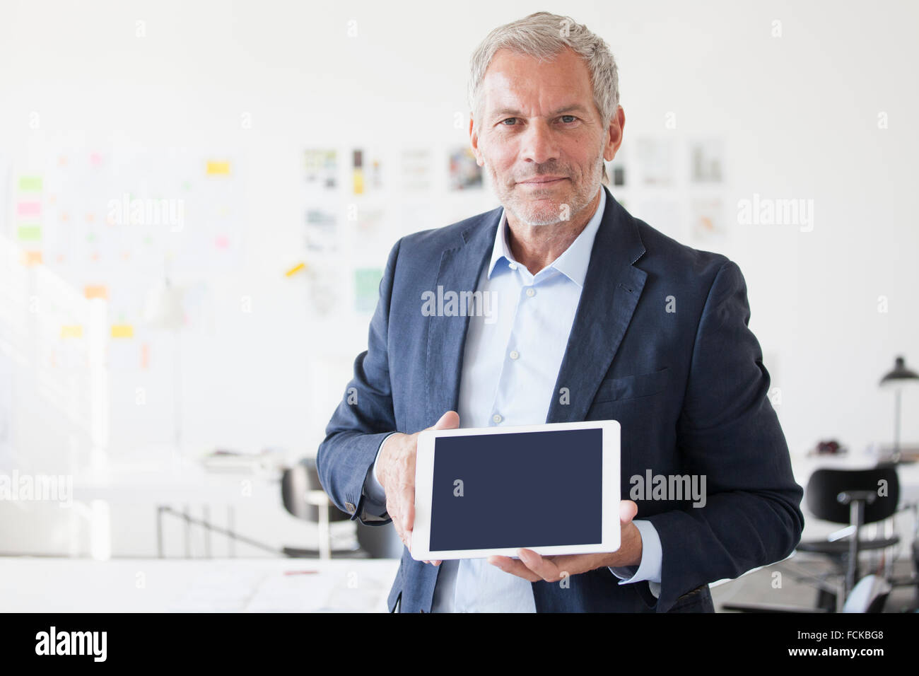 Portrait of businessman in office montrant l'écran est vide de digital tablet Banque D'Images