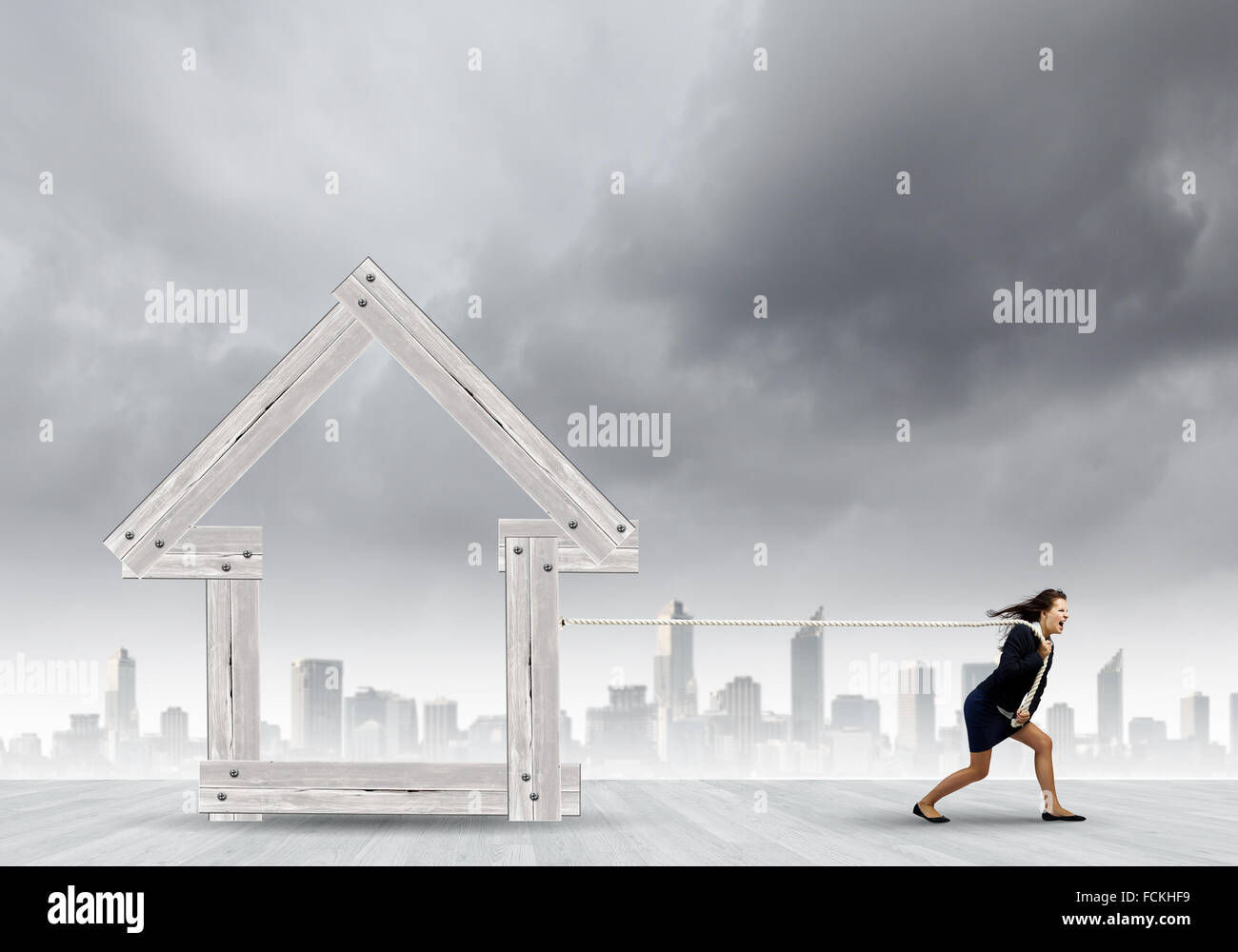 Les jeunes déterminés businesswoman pulling modèle maison en bois Banque D'Images Les jeunes déterminés businesswoman pulling modèle maison en bois Banque D'Images