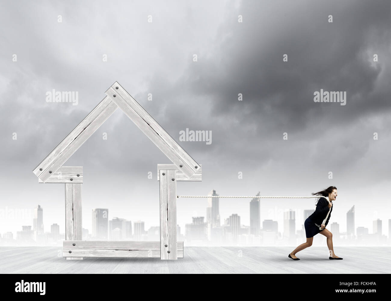 Les jeunes déterminés businesswoman pulling modèle maison en bois Banque D'Images Les jeunes déterminés businesswoman pulling modèle maison en bois Banque D'Images