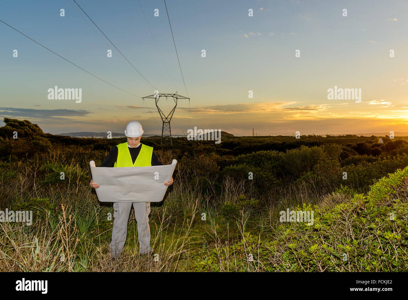 Ingénieur électrique, contrôle l'alimentation Line et les éoliennes au coucher du soleil en plein air à la campagne Banque D'Images