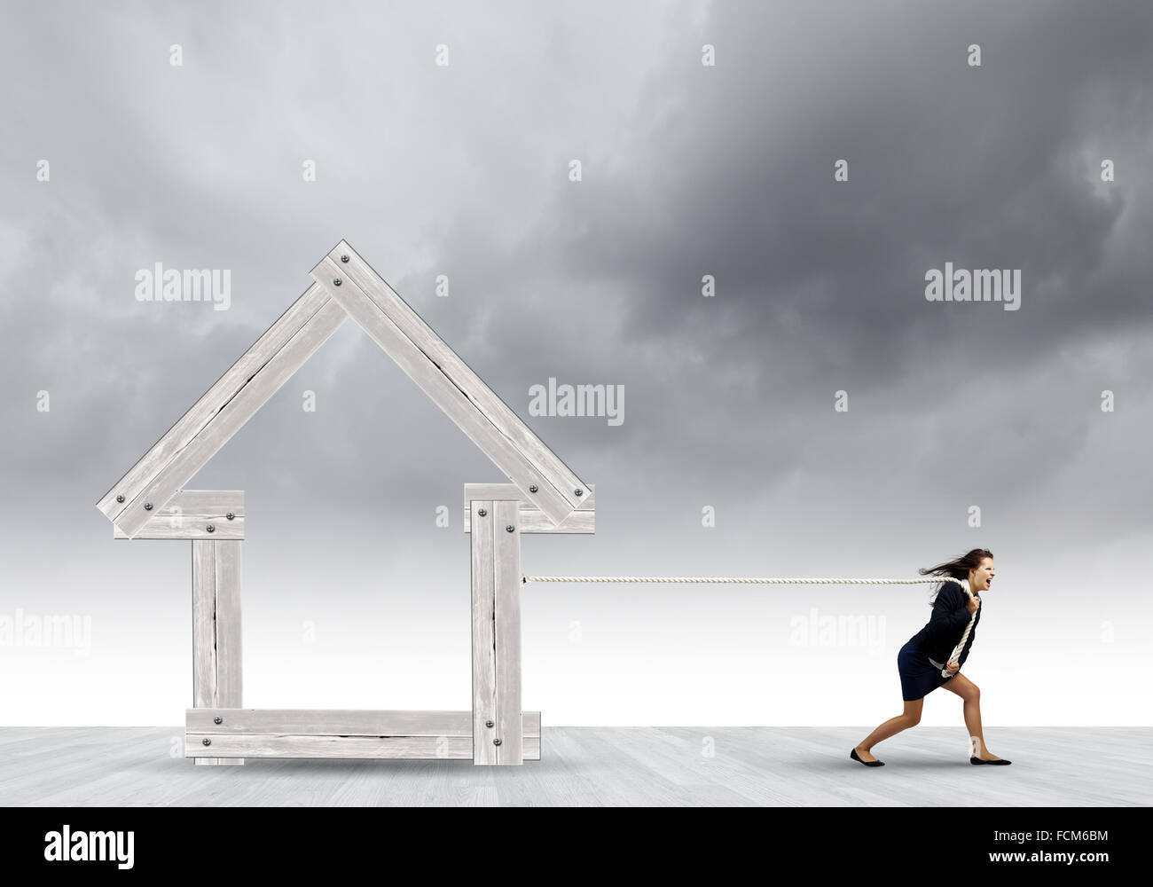 Les jeunes déterminés businesswoman pulling modèle maison en bois Banque D'Images Les jeunes déterminés businesswoman pulling modèle maison en bois Banque D'Images