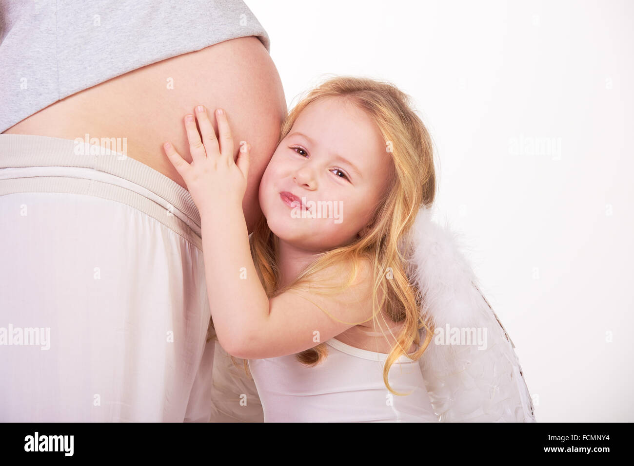 Belle blonde modèle ange cheveux hugs pregnant belly. Banque D'Images