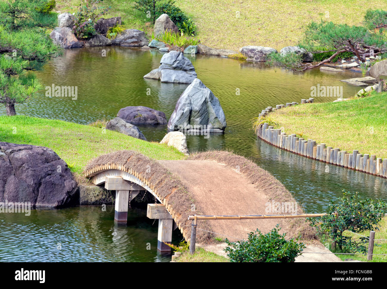 Chemin de jardin sur pont rustique dans le lac parc avec de grands rochers de granit et de pins verts, automne paysage japonais Banque D'Images