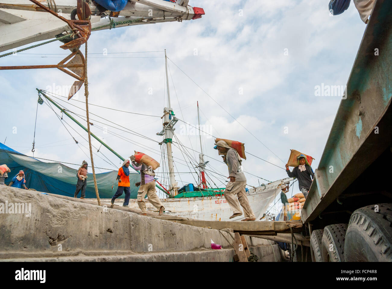 Travailleurs transportant des sacs de ciment d'un camion à un navire phinisi au port traditionnel de Sunda Kelapa à Penjaringan, dans le nord de Jakarta, Jakarta, Indonésie. Banque D'Images