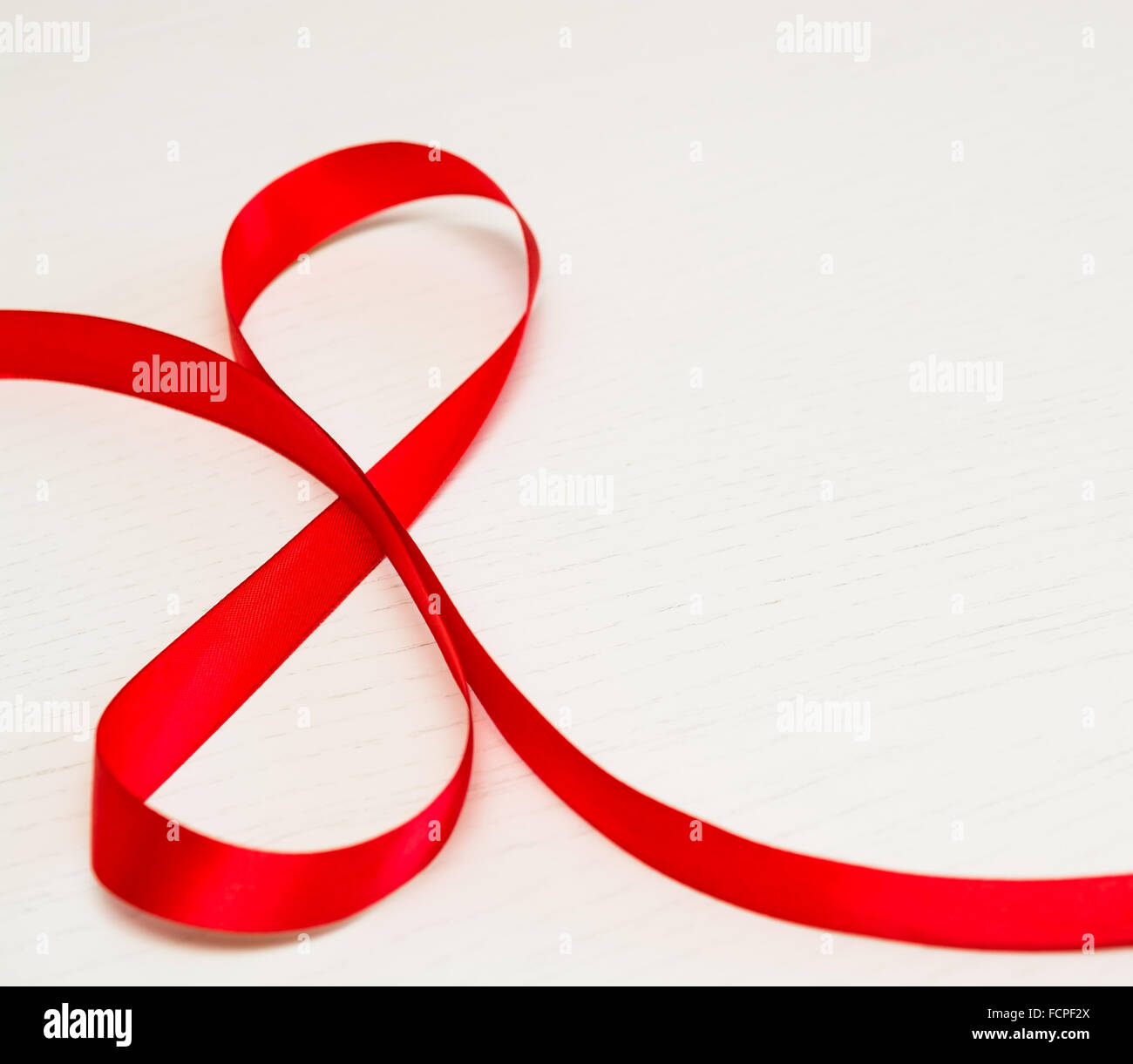 Bonne Journée de la femme. Ruban cadeau rouge en forme de 8 chiffres sur fond de bois blanc. Selective focus Banque D'Images