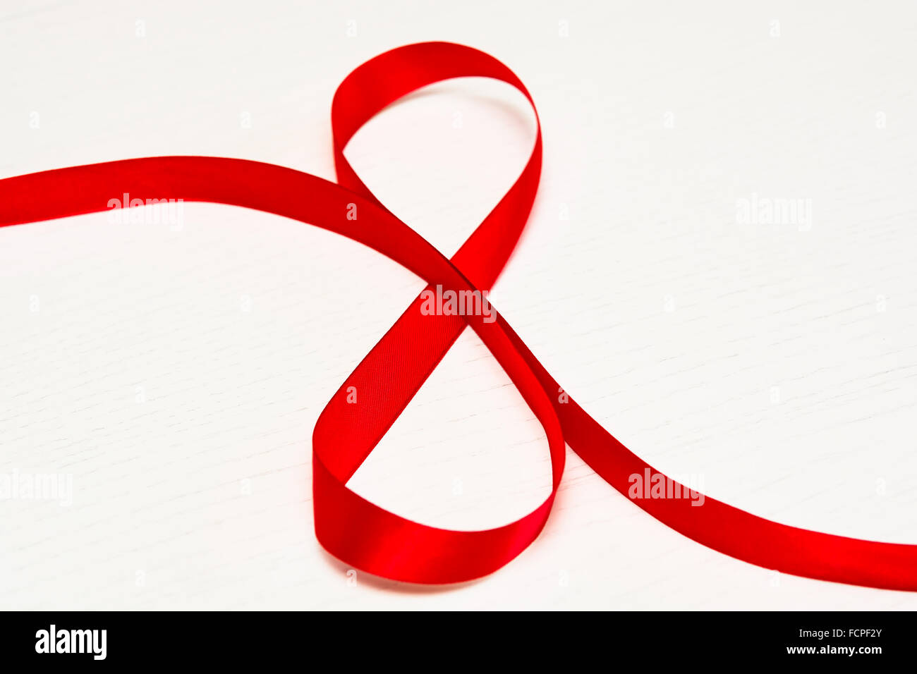 Bonne Journée de la femme. Ruban cadeau rouge en forme de 8 chiffres sur fond de bois blanc. Selective focus Banque D'Images