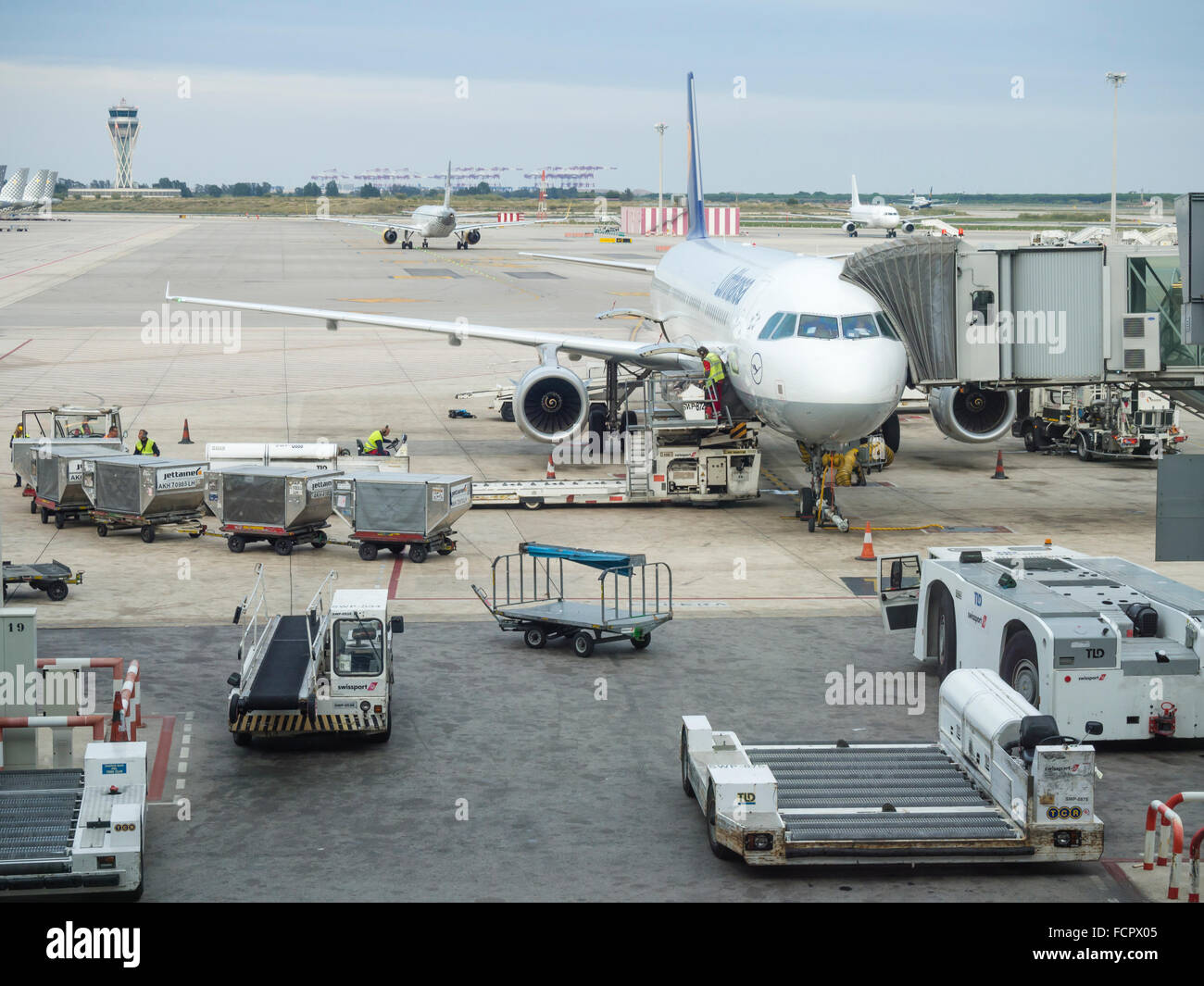 Les avions étant chargé à l'aéroport de Barcelone. Les travailleurs occupés, chariots à bagages, avion remorqueur tracteur. Banque D'Images