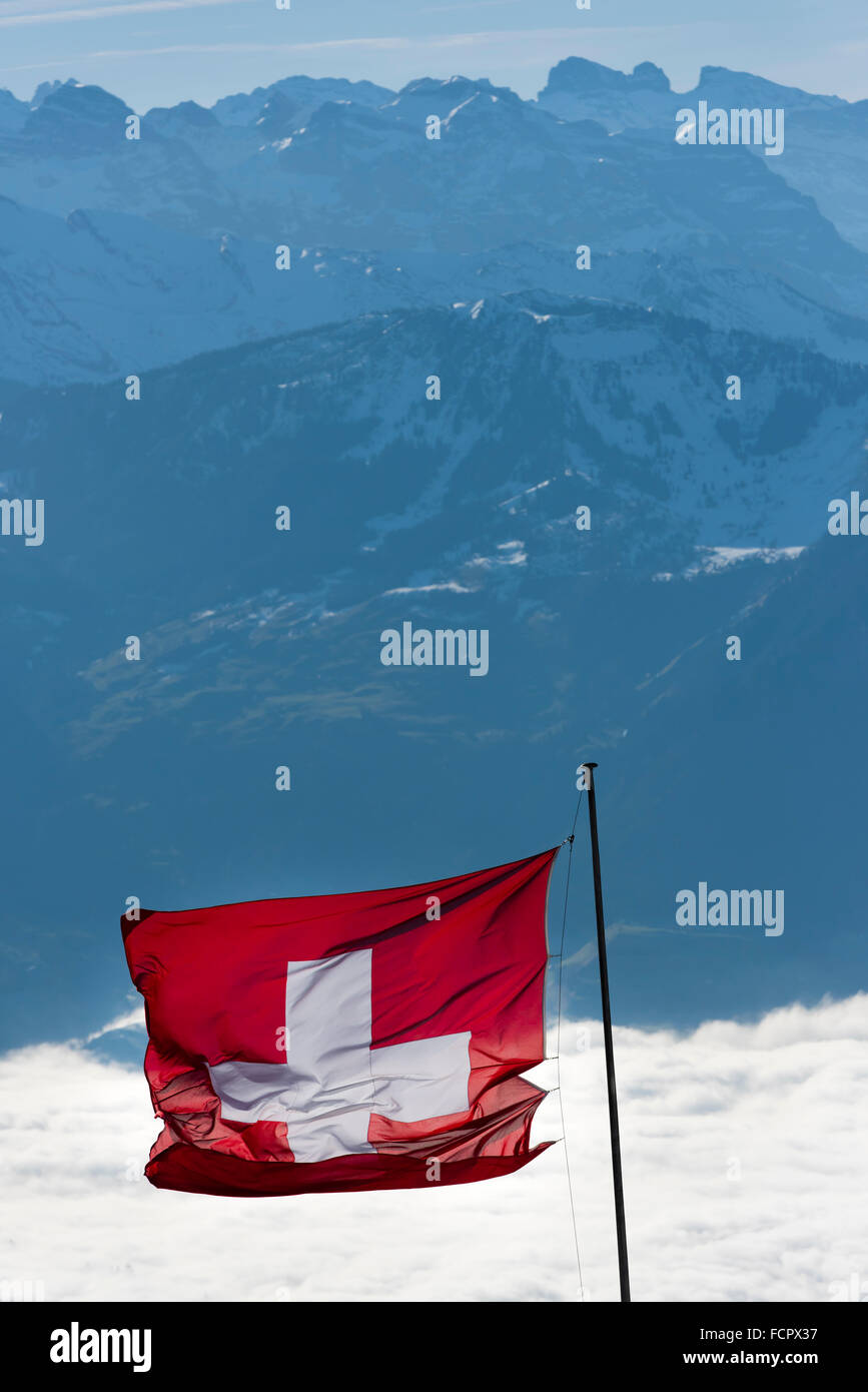 Le drapeau suisse est au vent au-dessus des nuages au sommet du Mont Rigi, Suisse Centrale. Banque D'Images