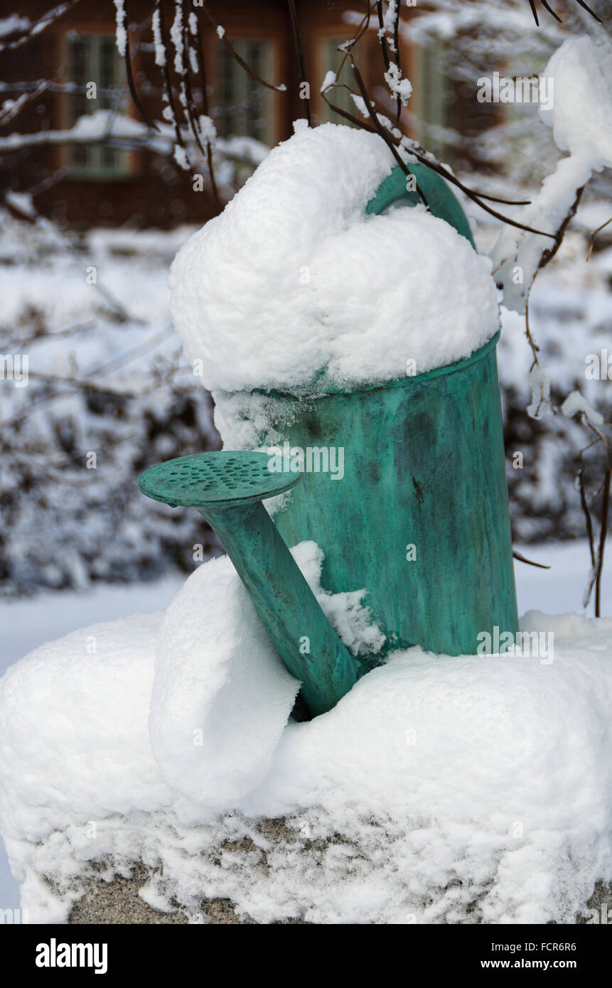 Un vieil arrosoir sur une pierre avec de la neige sur Banque D'Images