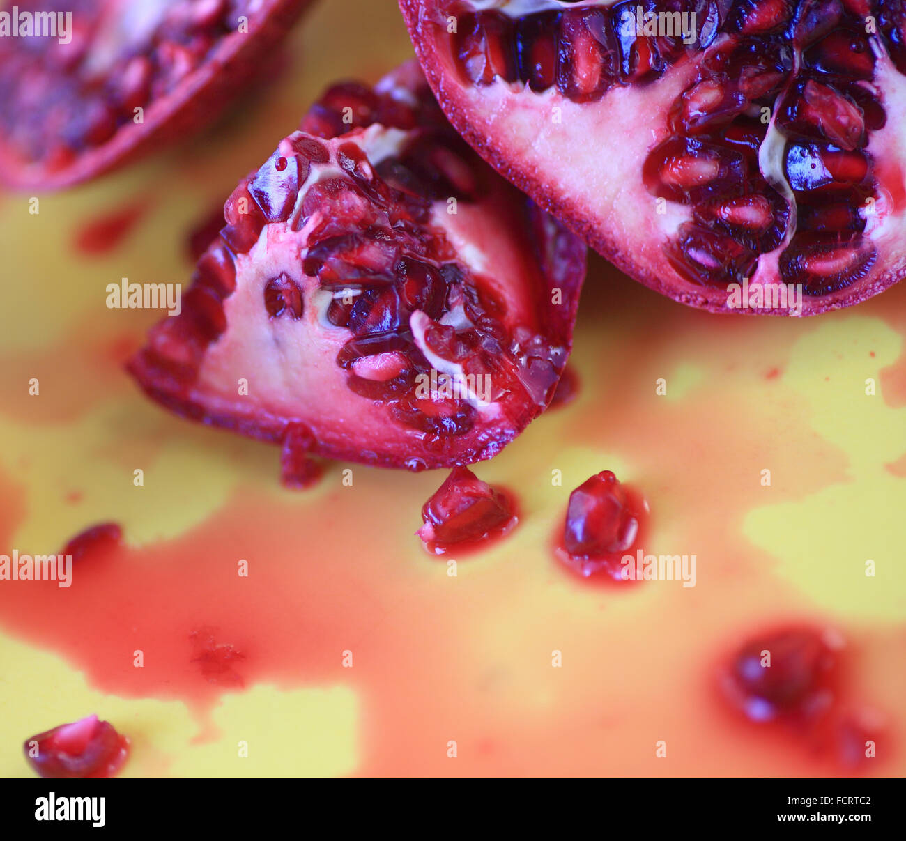 Couper les grenades juteuses sur fond jaune Banque D'Images