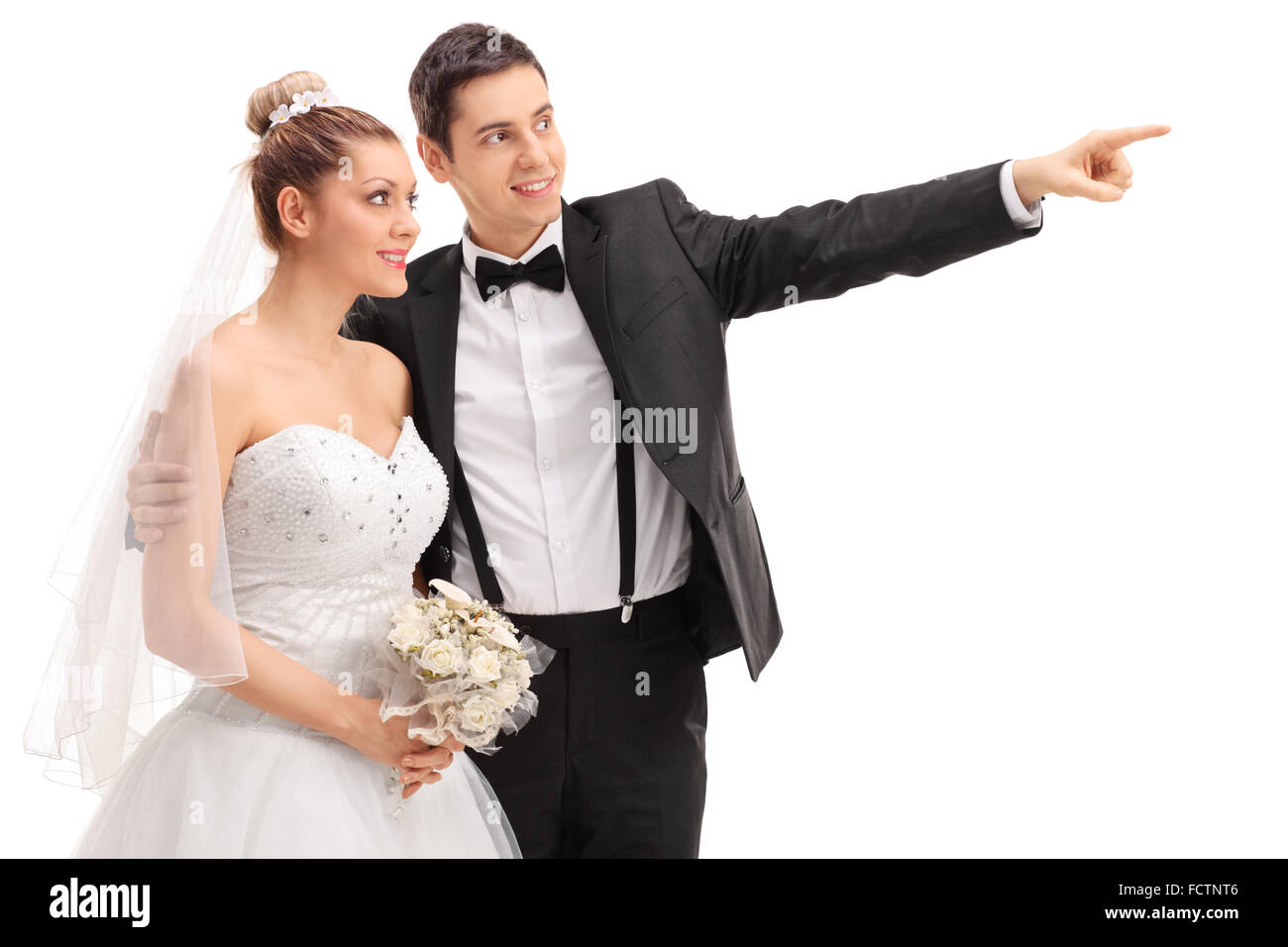 Les jeunes mariés montrant quelque chose à sa mariée et souriant isolé sur fond blanc Banque D'Images