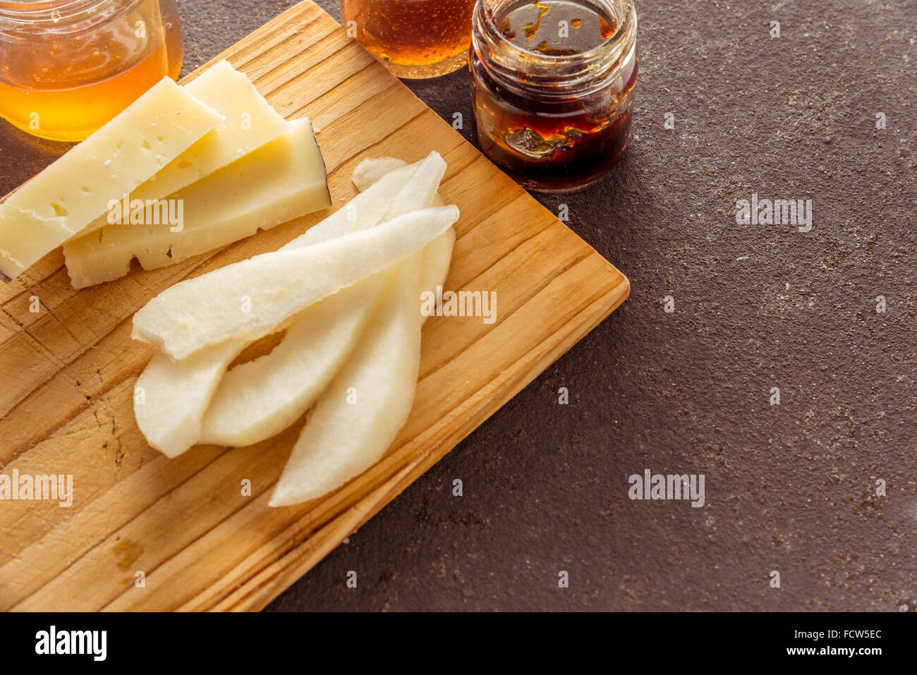 Une composition de tranches de fromage pecorino italien avec des confitures et les poires sur une planche à découper en bois Banque D'Images