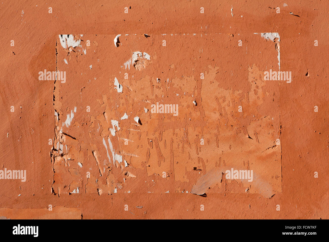 Des traces d'anciennes annonces vu sur le mur de stuc peint en terre cuite. La texture de fond. Banque D'Images