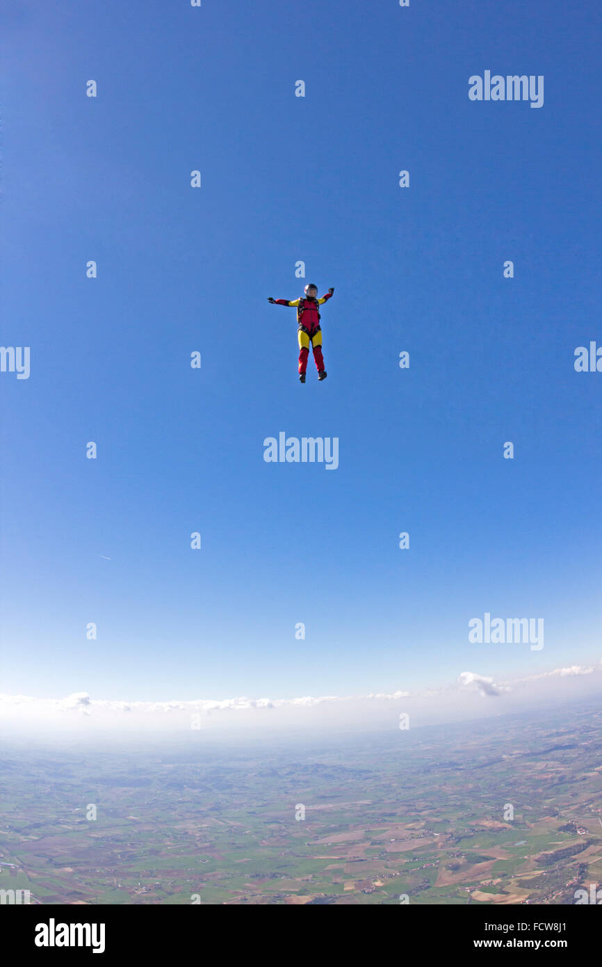 Un parachutiste girl vole dans une position debout dans le ciel bleu. Elle va ainsi obtenir une vitesse de 240 km/h vers le bas. Banque D'Images
