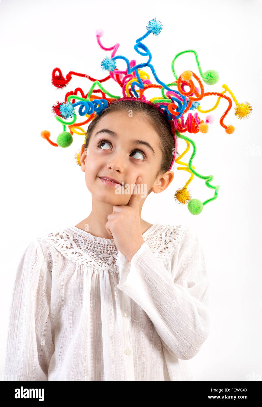 Jolie petite fille réfléchie avec une coiffure de streamers colorés tenant son doigt sur son visage alors qu'elle a l'air songeur en Banque D'Images