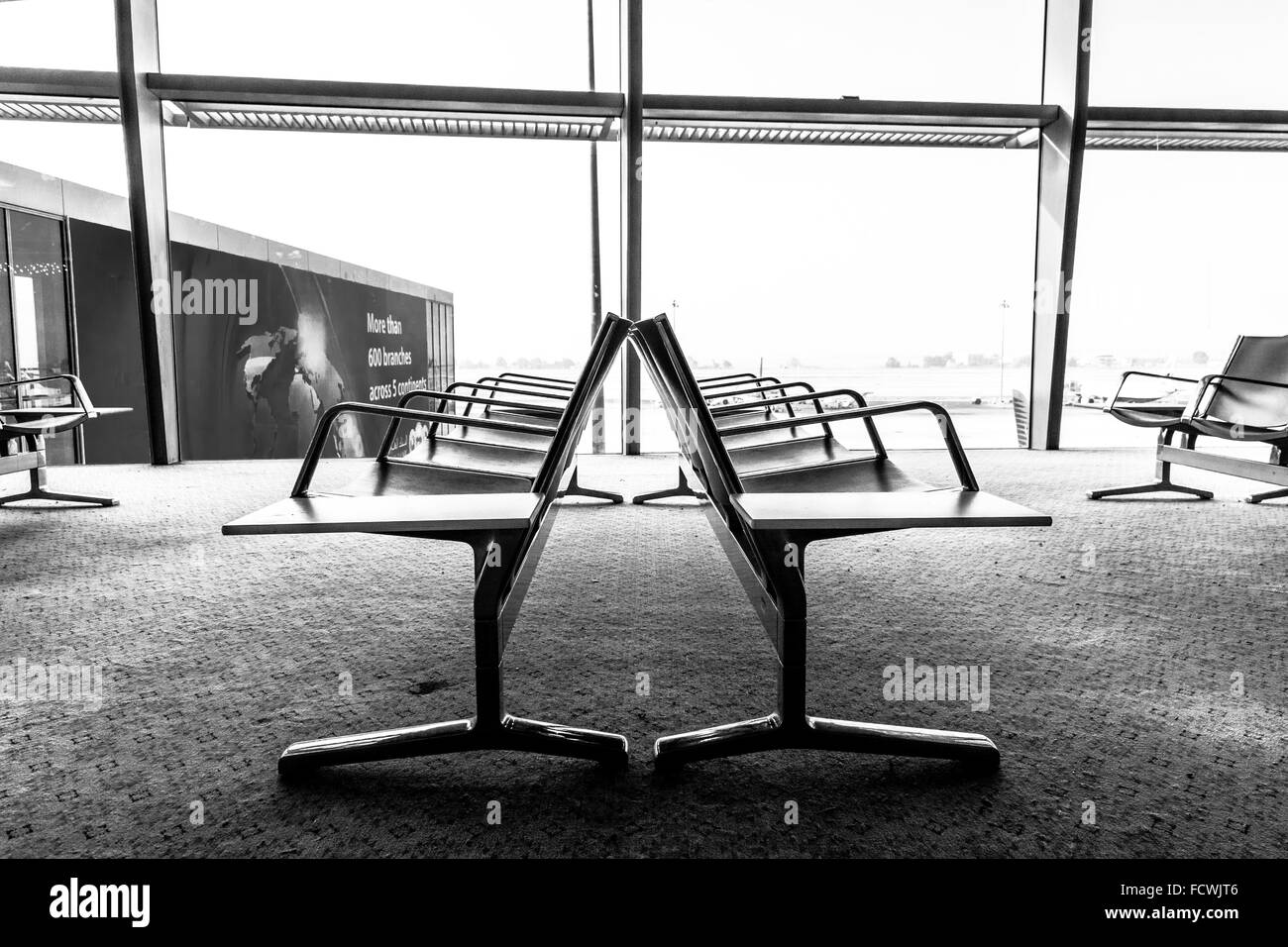 Vue de côté de l'aire d'attente de l'aéroport banc avec aucun peuple contre Windows Banque D'Images