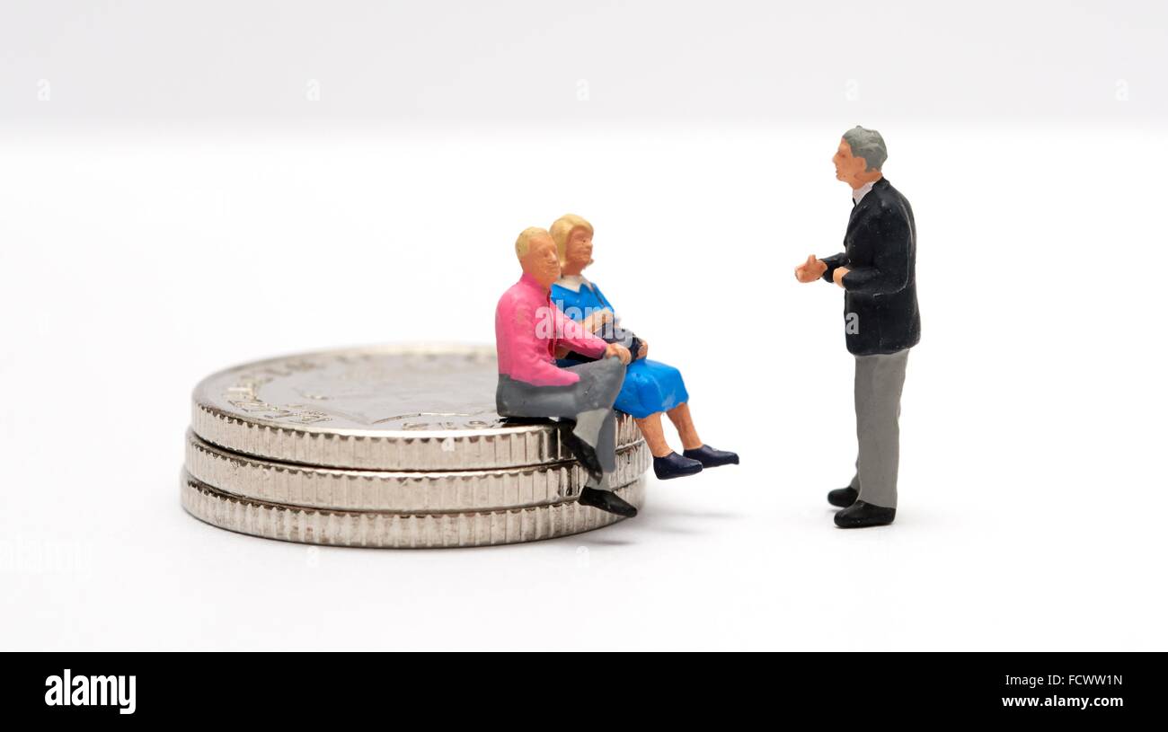 Conseils financiers étant accordée à un couple assis sur des pièces de monnaie Banque D'Images