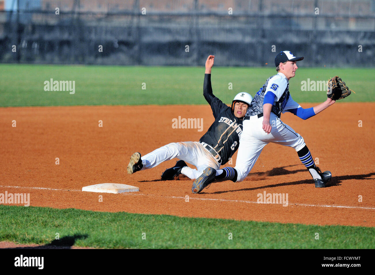 High school base runner glisse en toute sécurité dans la troisième base avec un vol de base que le joueur accepte un pas de la catcher. Banque D'Images