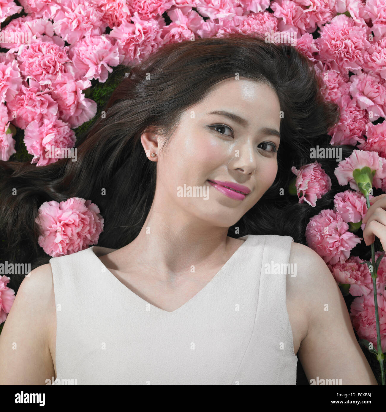 High angle de femme avec de longs cheveux entouré de fleurs et de carnation tenant sur d'eux et de l'avant Banque D'Images