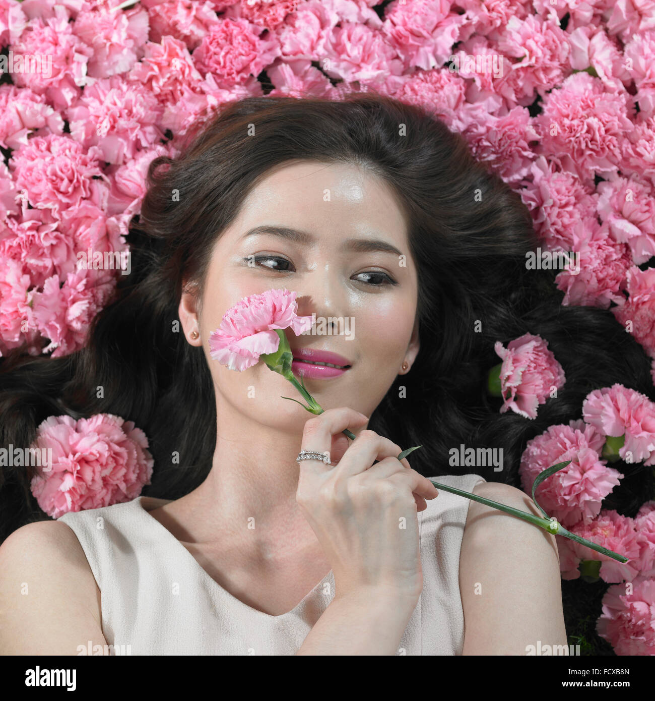 High angle of woman holding Flowers carnation et l'un d'entre eux sur son visage et à la bas Banque D'Images