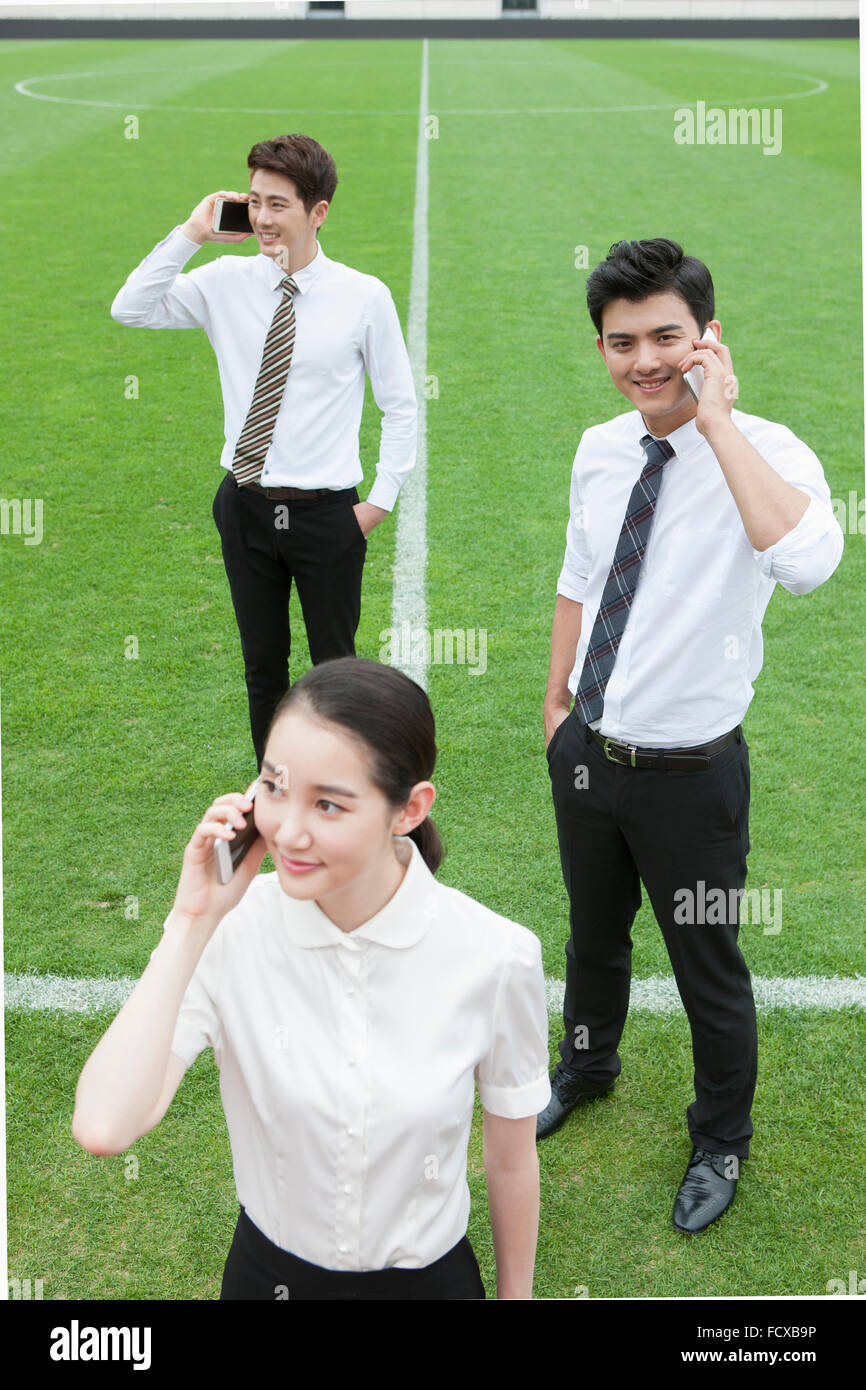 High angle d'une femme dans des tenues officielles de parler sur son téléphone et deux hommes debout derrière son parler sur un téléphone au Banque D'Images
