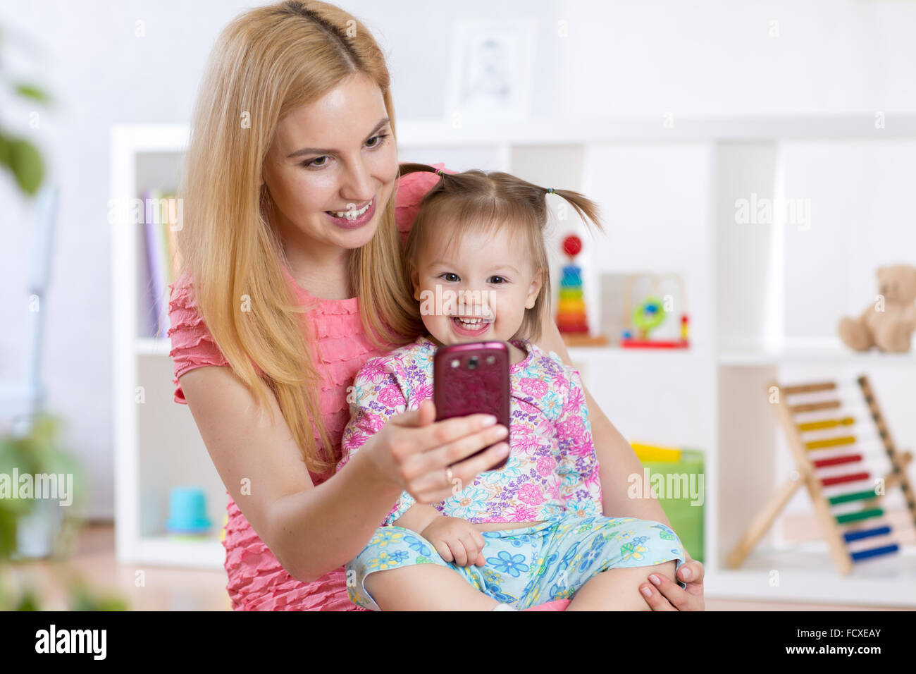Mère et son petit enfant fille en tenant sur une couverture selfies en maternelle prix Banque D'Images