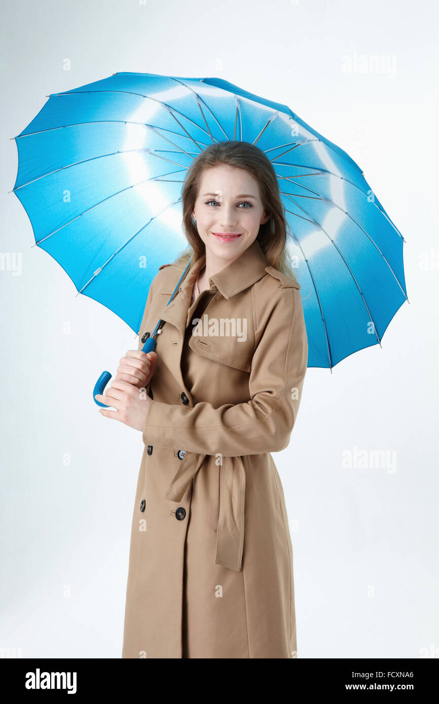 Young smiling woman with long hair wearing blue parapluie et imperméable à regarder avant Banque D'Images