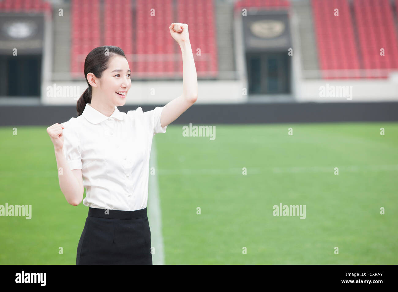 Portrait of woman in suit cheering at stadium Banque D'Images