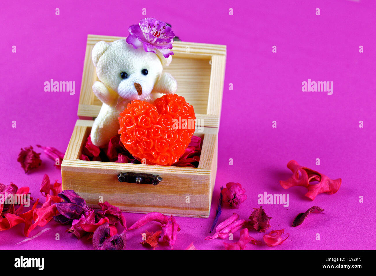 Petit ours en peluche tenant l'amour en boîte en bois. Fond rose Banque D'Images