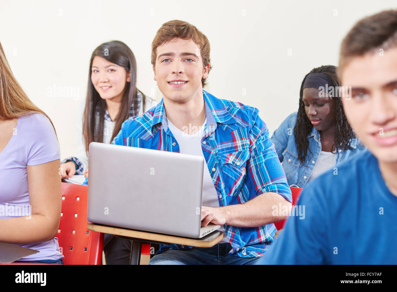 Élève en classe avec un ordinateur portable avec un sourire Banque D'Images