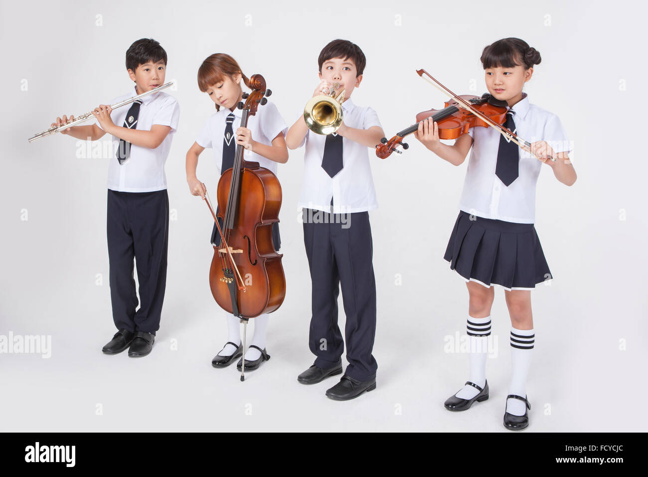 Quatre étudiants du primaire en uniforme debout à côté de l'autre et de jouer un instrument de musique classique chaque Banque D'Images