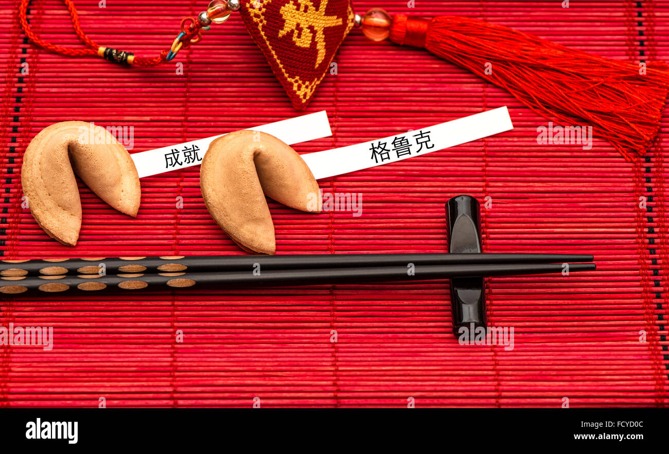 Nouvel An chinois porte-bonheur, fortune cookies et Baguettes en bambou noir sur rouge mat. Texte d'exemple de succès et de bonheur Banque D'Images