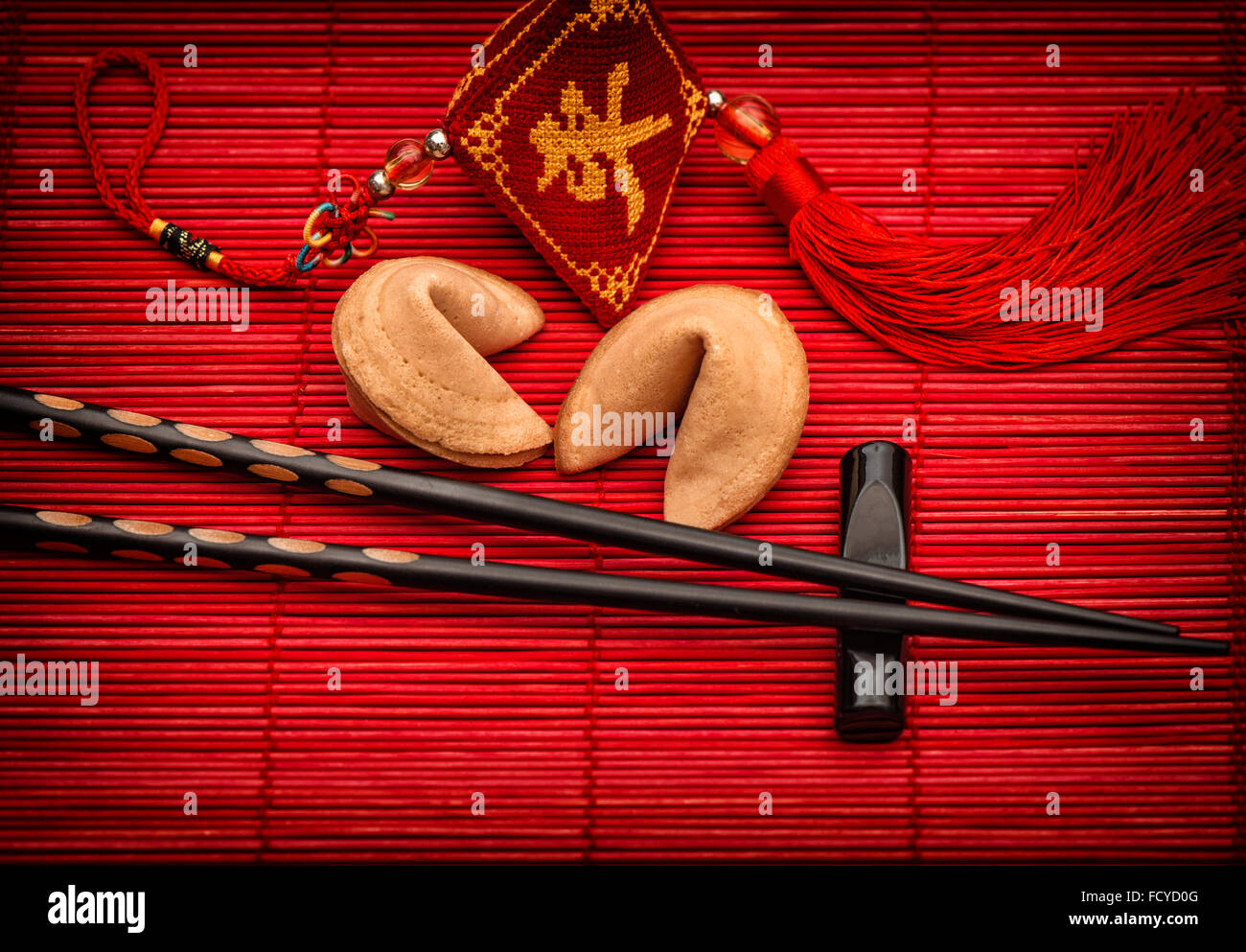 Arrière-plan de style asiatique avec Lucky Charm, fortune cookies et Baguettes en bambou noir sur rouge mat. Le nouvel an chinois Banque D'Images