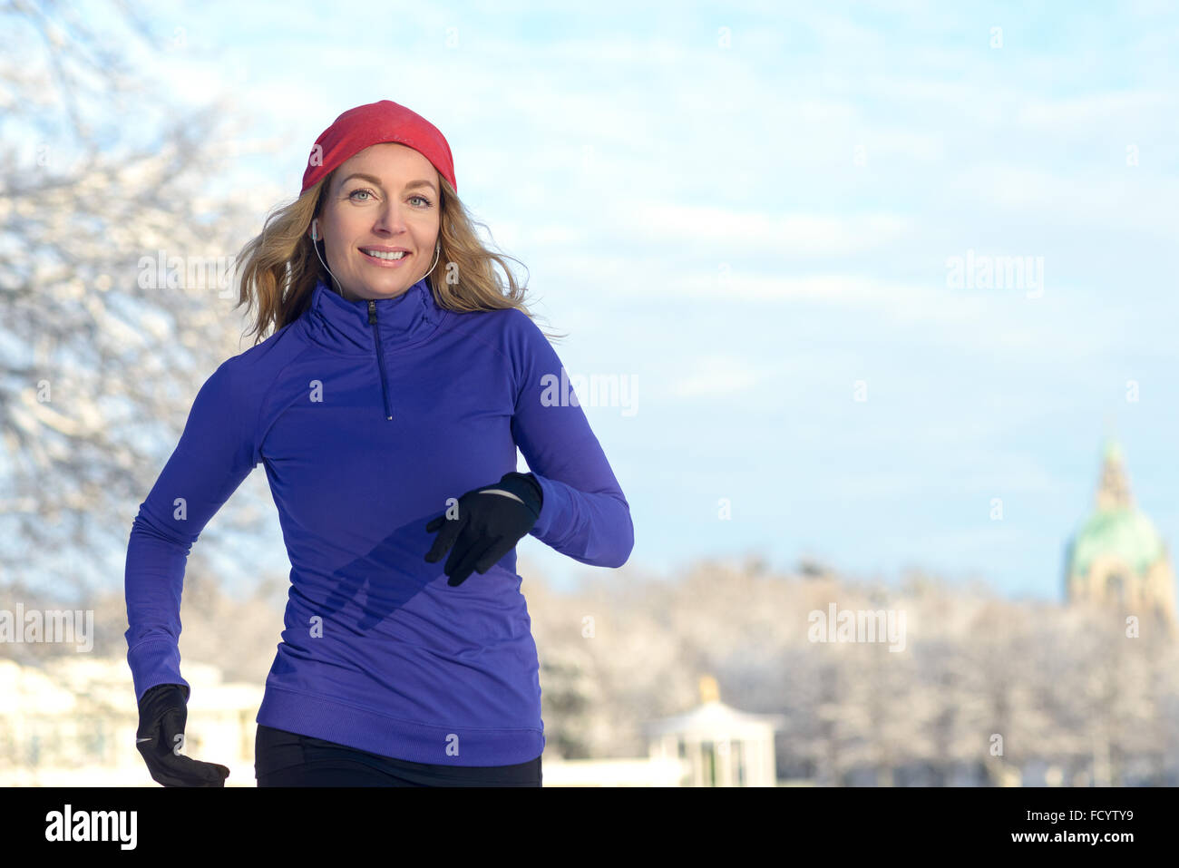 Full Body Shot d'une jolie femme athlétique Jogging en hiver avec écouteurs  et une tenue d'hiver, souriant à la caméra, avec l'exemplaire s Photo Stock  - Alamy