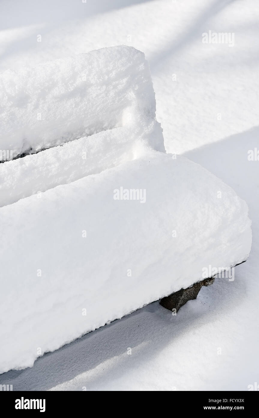 Banc dans un parc entièrement couvert par la neige après les fortes chutes de neige Banque D'Images