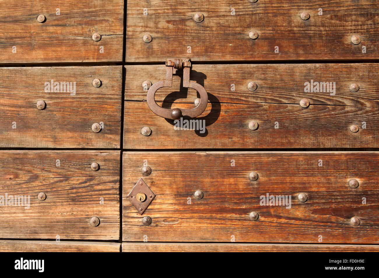 Vieux métal doorknocker sur la barrière en bois fixés avec des rivets à Bergame, Lombardie, Italie. Banque D'Images