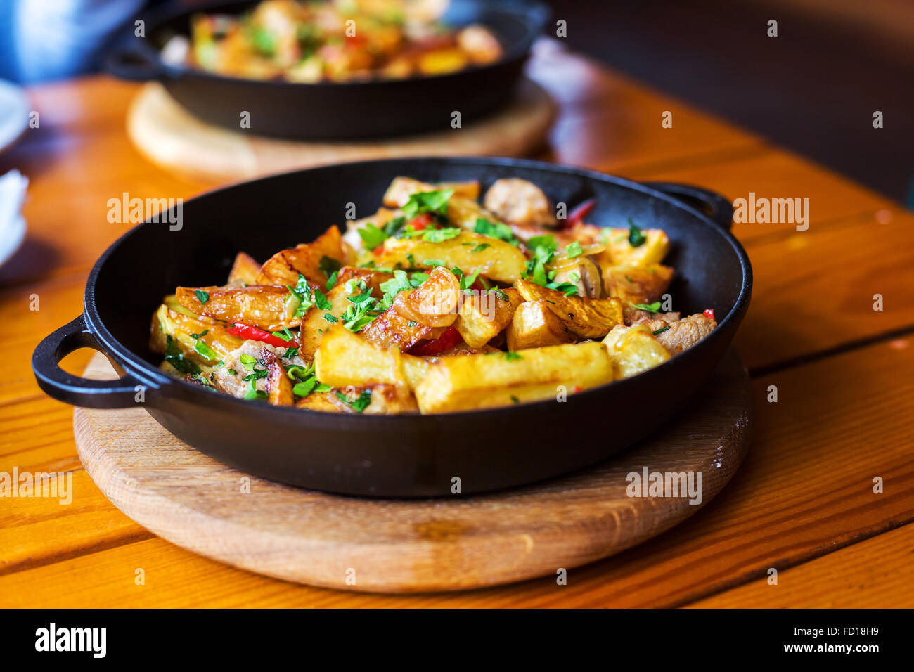 D'authentiques frites avec du bacon et du persil sur noir pan. Matin, à la mode d'éclairage atmosphérique spot branché soft focus. Banque D'Images