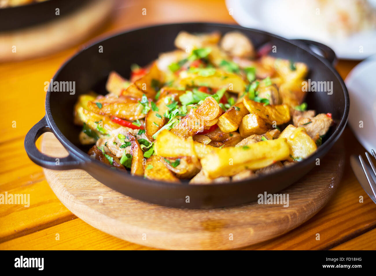 D'authentiques frites avec du bacon et du persil sur noir pan. Matin, à la mode d'éclairage atmosphérique spot branché soft focus. Banque D'Images